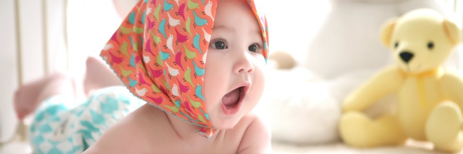 Baby mit Kopftuch auf Spieledecke.