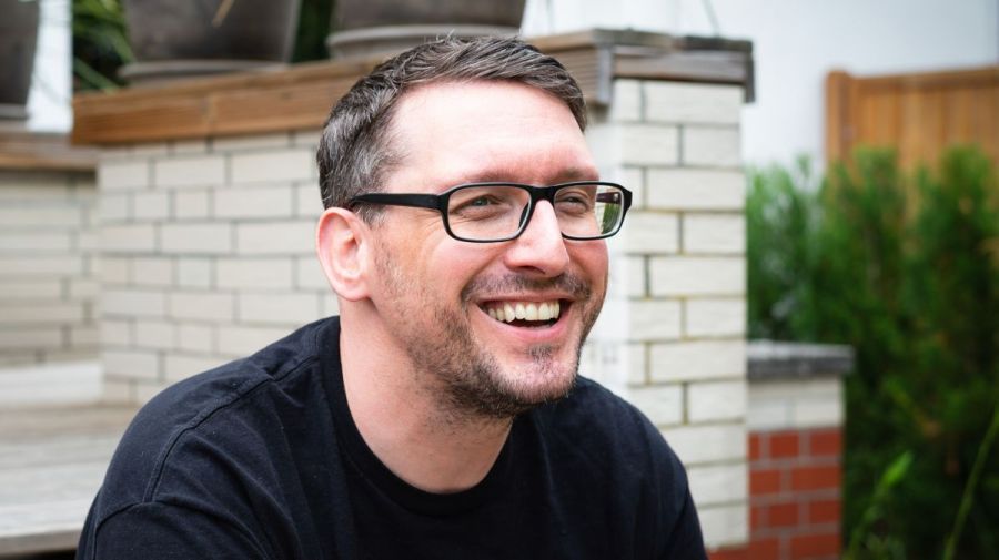 Stefan Kübler sitzt auf der Terrasse und lächelt.