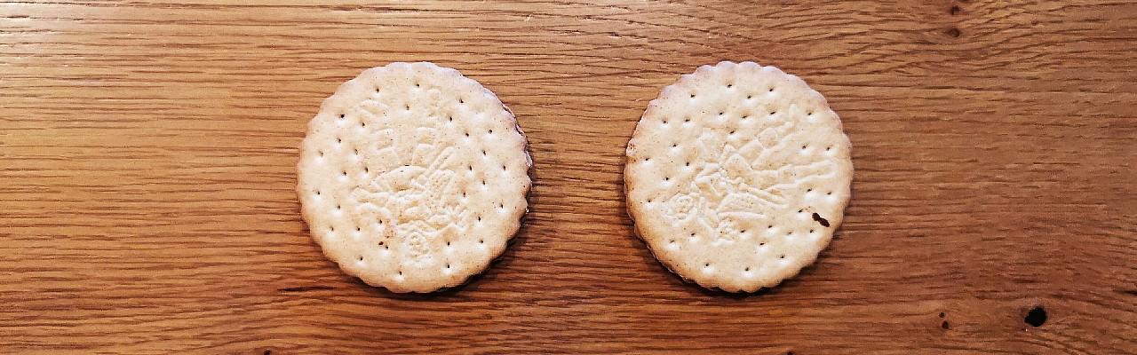 Draufsicht auf zwei Kekse auf einem Esstisch.