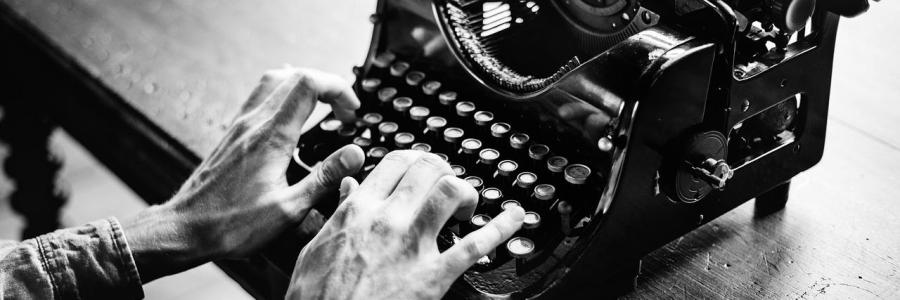 Schwarz-weiß-Foto einer Schreibmaschine mit Händen auf der Tastatur.