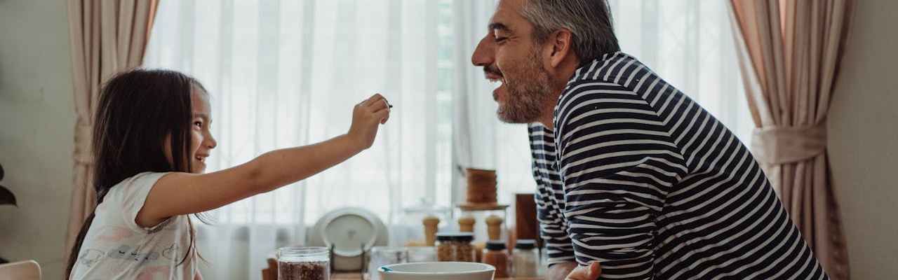 Vater und Tochter sitzen zusammen und gut gelaunt am Esstisch.